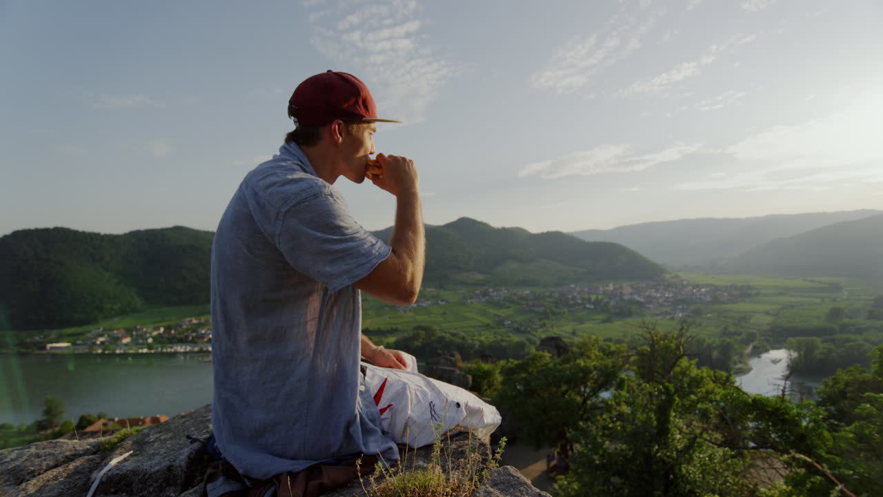 picnic pacifico sul crinale della montagna, uomo che fa una pausa nel campo di fiori, torre di pietra, godendo della vista, ammirando la vista, panoramica del paesaggio, slow motion cinematografico slomo, uomo che ama le colline all'aperto