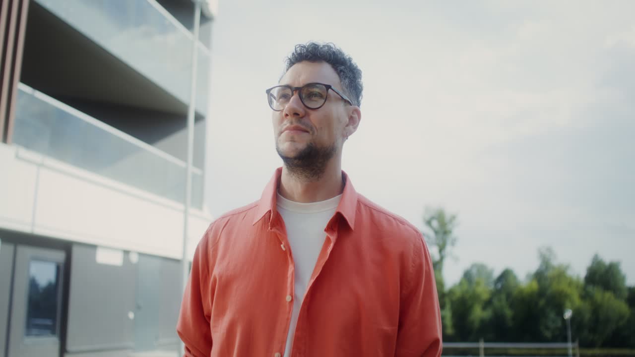 hombre en camisa de coral fuera del edificio moderno