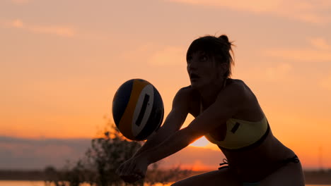 Mitteldistanz-Volleyball-Mädchen-Im-Bikini,-Das-Bei-Sonnenuntergang-Auf-Dem-Platz-Auf-Den-Ball-Wartet-Und-Während-Eines-Spiels-Am-Strand-In-Zeitlupe-Einen-Unterarmpass-Gibt.