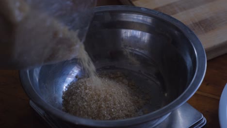 Gießen-Von-Braunem-Zucker-In-Edelstahlschüssel-Zum-Backen