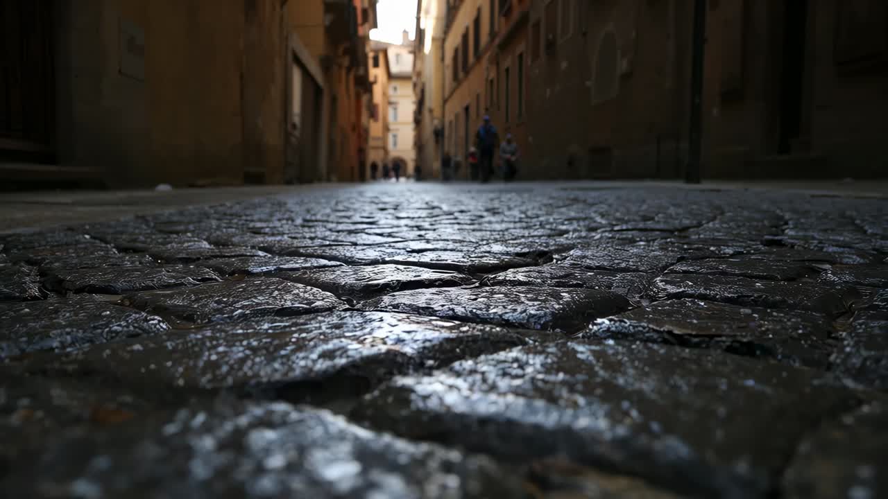 Tracking low camera moving forward over wet cobblestone pavement in narrow alley, revealing bicycle