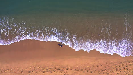 Woman-walking-in-wet-sand-on-beach-washed-by-ocean-waves-in-Thailand