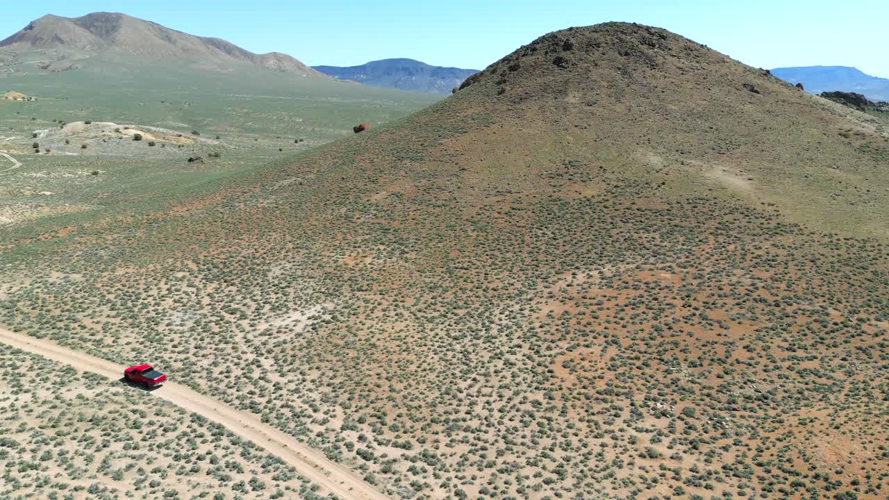 ⁇ 은 트럭이 밝은 초록색과 다채로운 모래로 봄에 네바다 사막을 가로질러 도로를 벗어나고 있는 공중 전망