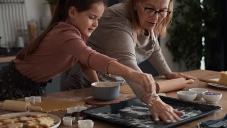 chica caucásica preparando galletas caseras con su abuela
