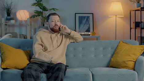 man talking on phone while relaxing on couch at home