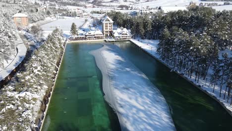 Fly-over-mountain-lake,-half-covered-in-ice