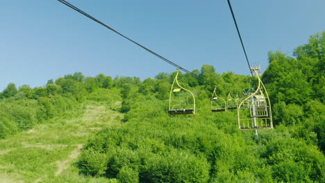 Seats-Of-The-Ski-Lift-They-Move-Upwards-Against-The-Background-Of-A-Forest-Covered-With-A-Forest-Hol