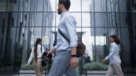 smiling businessman holding smartphone at modern office building. downtown area