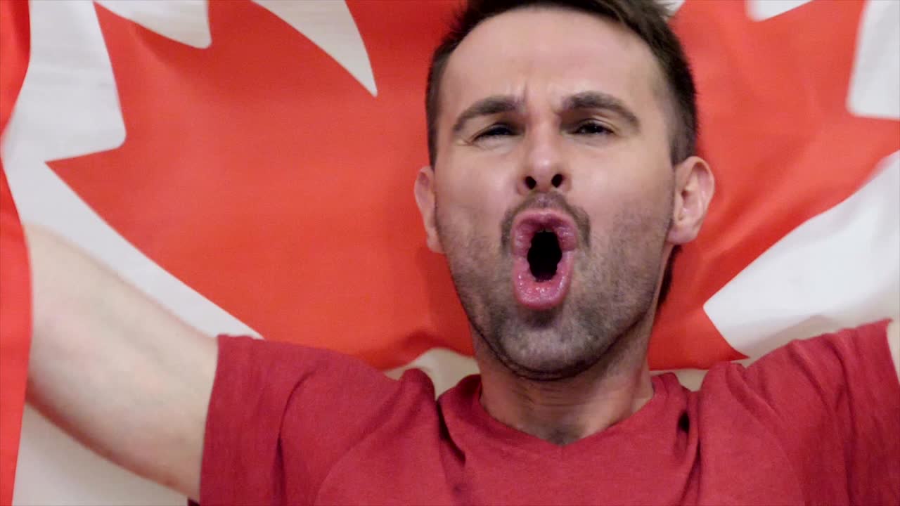 un aficionado canadiense celebra sosteniendo la bandera de canadá en cámara lenta, 4k, de alta calidad