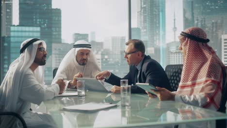 international business consultant advices on diversification of investment portfolio to successful arab company owners. multicultural meeting in modern office between american and emirati businessman