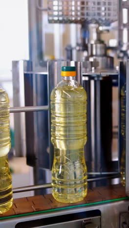 contemporary olive oil factory background. sunflower oil in bottles moving on a production line inside the factory. plastic bottles with packed cooking oil on a conveyor. vertical video
