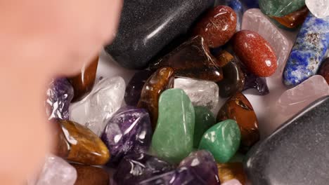 detailed view of tweezers sorting vibrant gemstones on a white surface, highlighting texture and color.