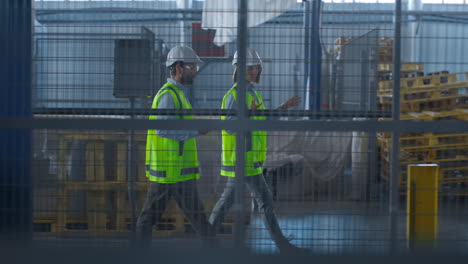 two uniformed warehouse workers discussing manufacture production inspecting