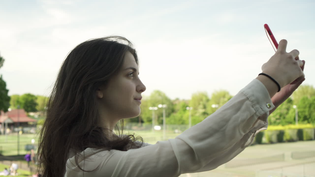 joven italiana con smartphone tomando selfie al aire libre en un parque en londres