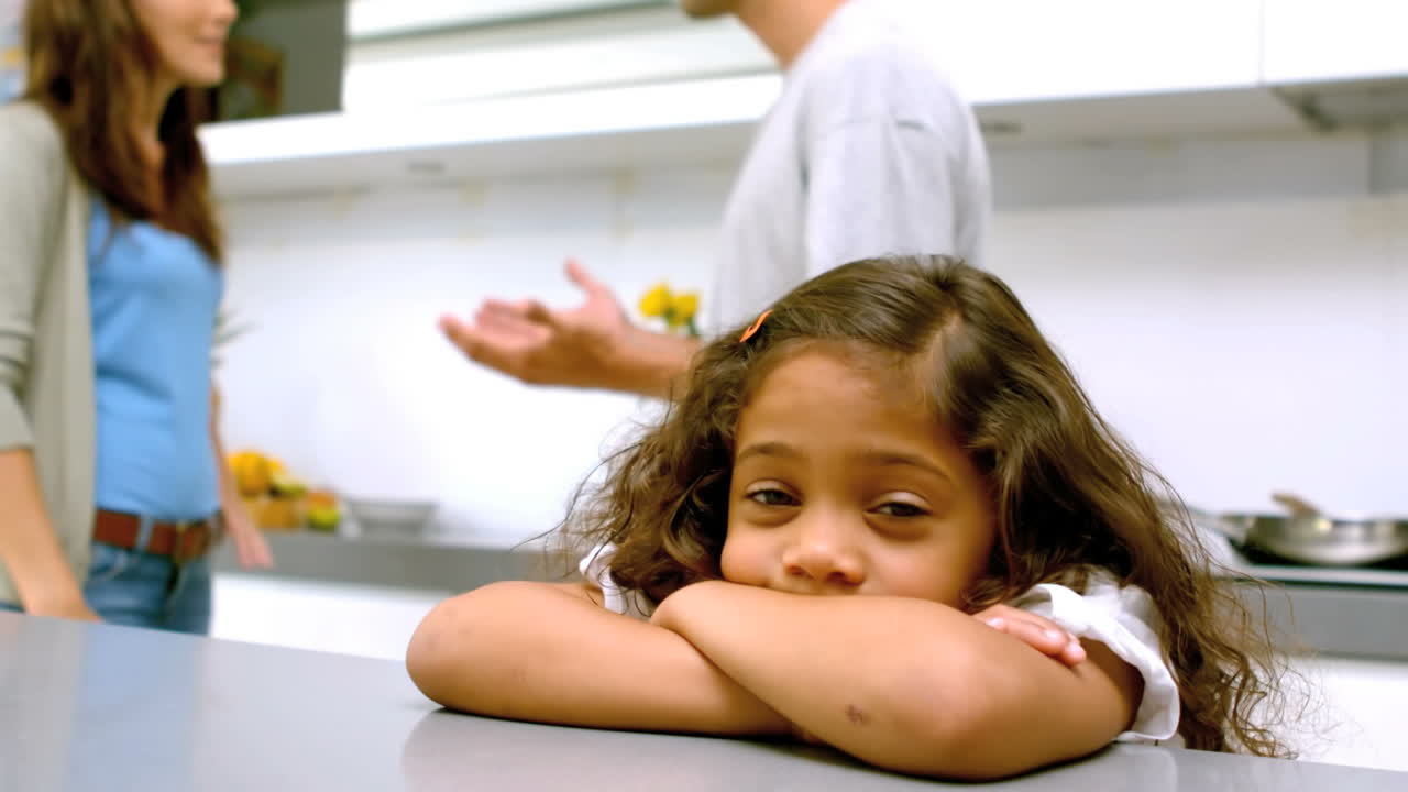 niña triste con los brazos cruzados mientras los padres pelean