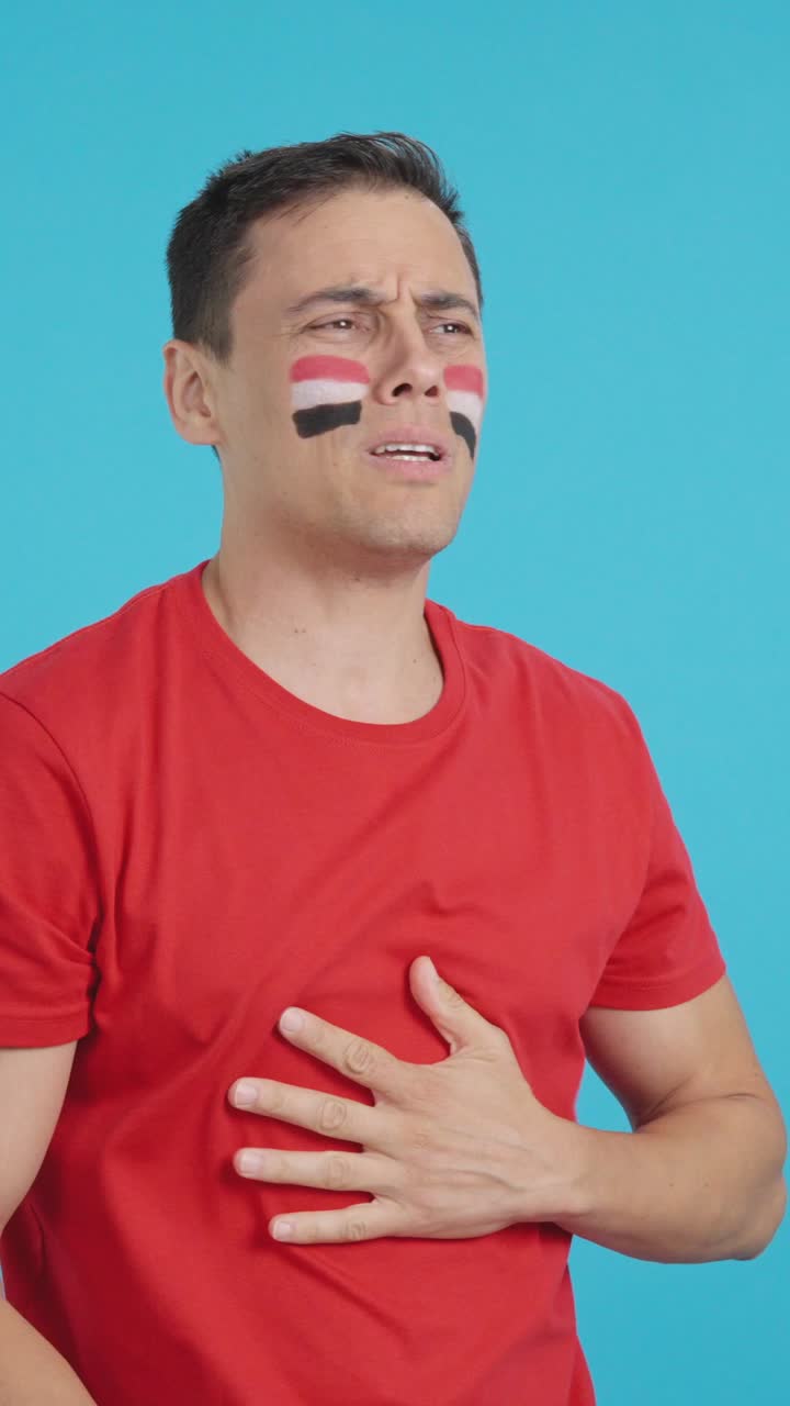 Nervous man cheering for Egypt during a match looking away