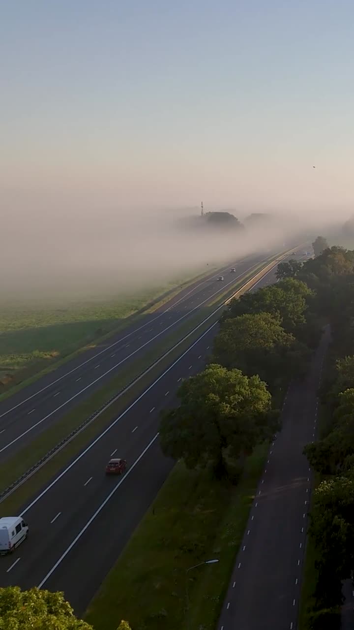 Aerial view of a highway at dawn with fog