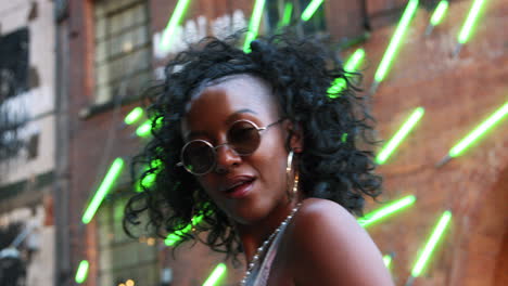 joven negra a la moda en una calle urbana caminando hacia la cámara y en foco, de cerca, ángulo bajo, luces borrosas de neón en el fondo