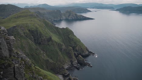 Scenic-view-from-top-of-mountain-in-Norway-to-fjord-at-Runde,-motion-handheld