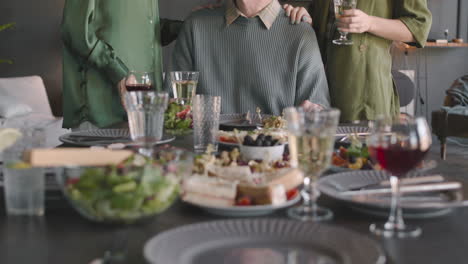 Portrait-Of-A-Happy-Father-And-His-Two-Adult-Daughters-Smiling-And-Toasting-At-Camera-At-Home