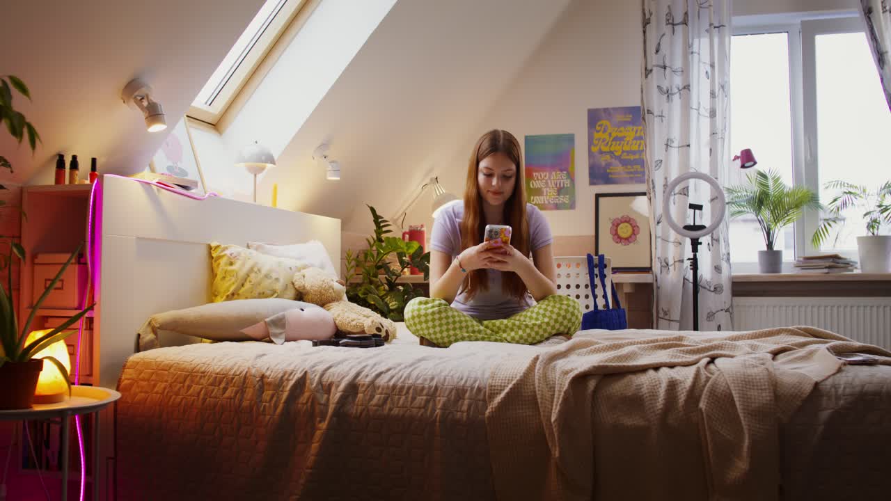 una adolescente usando un teléfono inteligente en su dormitorio
