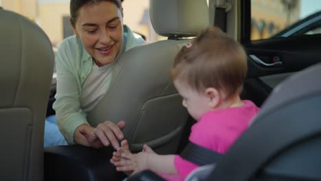 mother buckling her baby into a car seat