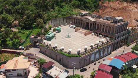 cinematic drone descent showcasing a majestic columned structure with courtyard, set against lush greenery in the philippines
