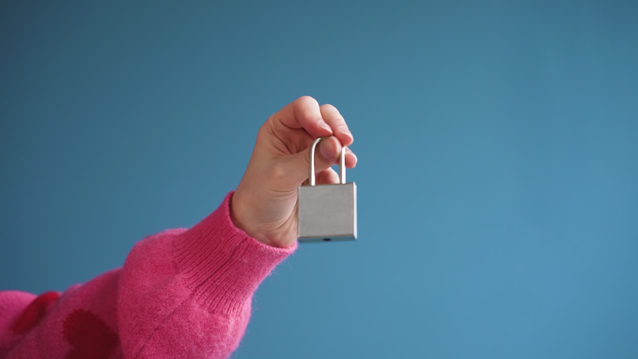 Video dettagliato ravvicinato di mani che aprono un lucchetto a forma di cuore con una chiave. Simboleggia fiducia, apertura e dare accesso al proprio cuore. Perfetto per campagne di San Valentino e contenuti sulle relazioni.
