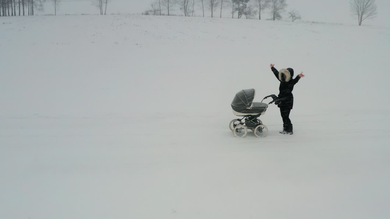 madre con cochecito agita las manos para pedir ayuda durante las fuertes nevadas de invierno