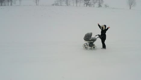 mother with baby carriage wave hands for help during severe winter snowfall