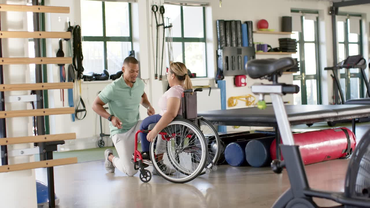 Helping woman with paraplegia in wheelchair, physical therapist guiding rehabilitation exercises