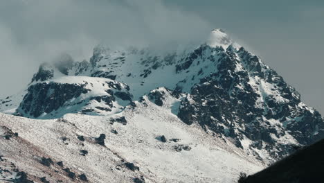 clouds and fog over the mountain covered in snow in winter