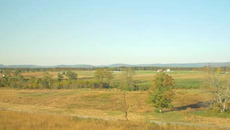 Hermosa-Vista-Panorámica-De-Los-Pastizales-Cubiertos-De-Hierba-Amarilla-Y-Verde-Y-Un-Bosque-Y-Cabañas-A-Distancia-En-Un-Día-Soleado-Cerca-De-Los-Campos-De-Batalla-De-La-Guerra-Civil-Cerca-De-Gettysburg,-Pa-Usa