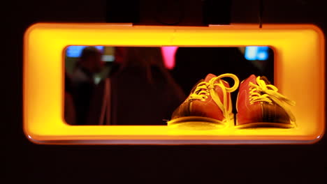 a young woman grabs a pair of shoes under the neon lights at the bowling alley