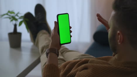 man is calling by video chat in smartphone from home or office at break time green screen on gadget app for online communicating and chatting