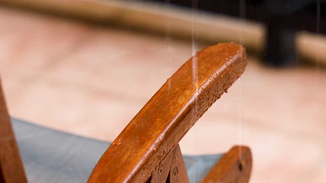 rain water splashing a mahogany wooden armchair outside on the terrace