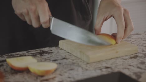 una persona corta una manzana fresca y jugosa en una tabla de cortar de madera