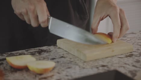 person slices fresh juicy apple on wooden chopping board