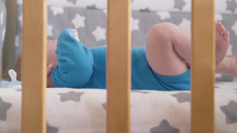 Besorgtes-Kind-Weint-Und-Tritt-Mit-Den-Beinen-Und-Dem-Schnuller-Im-Modernen-Kinderbett