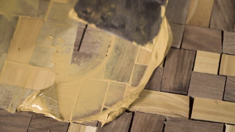 Close-shot-of-a-spatula-spreading-wooden-paste-on-a-wood