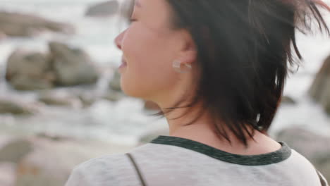 retrato de una hermosa mujer asiática sonriendo disfrutando de la playa nublada explorando el estilo de vida de vacaciones con el viento soplando el cabello en la playa