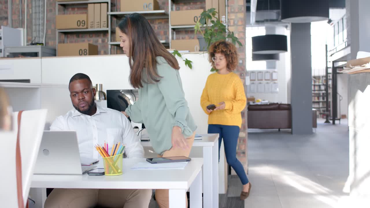 Colegas diversos usando notebook e discutindo trabalho na mesa do escritório, espaço para texto, câmera lenta.