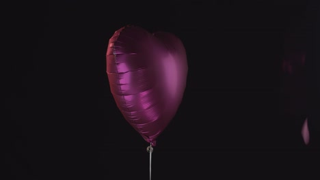 un globo de corazón rosa brillante con corazones rosas cayendo a su alrededor
