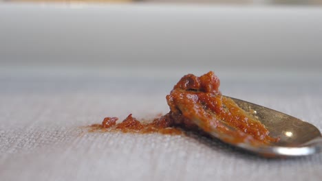 a spoon with red sauce on a tablecloth