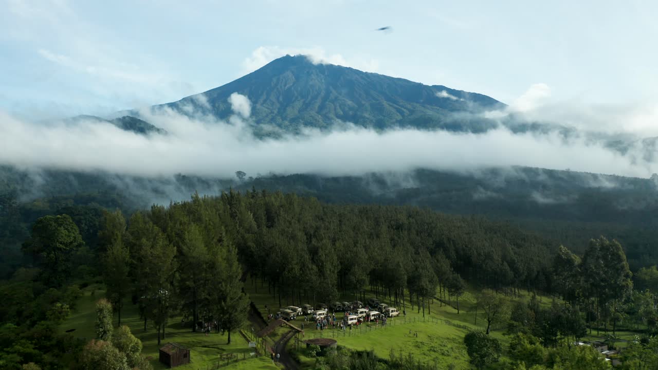 Aerial pan drone shot above trees revealing the forest and mountain horizon looking at a volcano and clouds beautiful nature jungle of Tanzania 4k