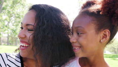retrato en cámara lenta de una madre sonriente con niños relajándose en el parque