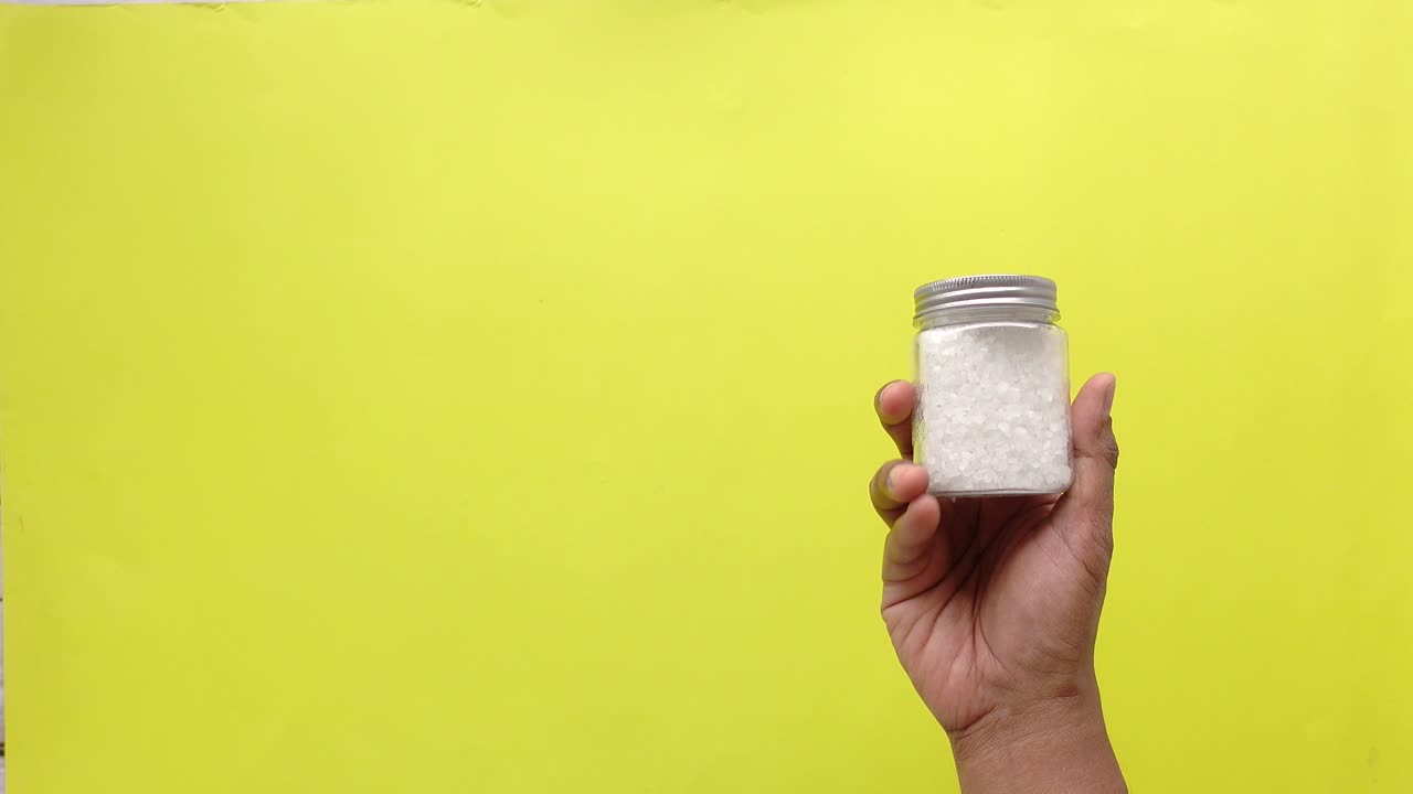 A hand holding a jar of salt