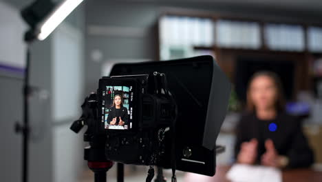 confident female speaker wearing black jacket filming a video. close up view of the professional camera recording a speaker.