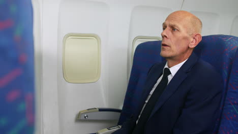 an impatient mature business man waiting for take off on an airliner airplane sitting in the cabin looking at his watch