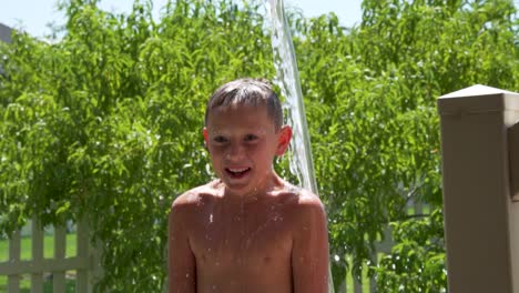 niño en un caluroso día de verano recibe un balde de agua tirado en su cabeza - cámara lenta